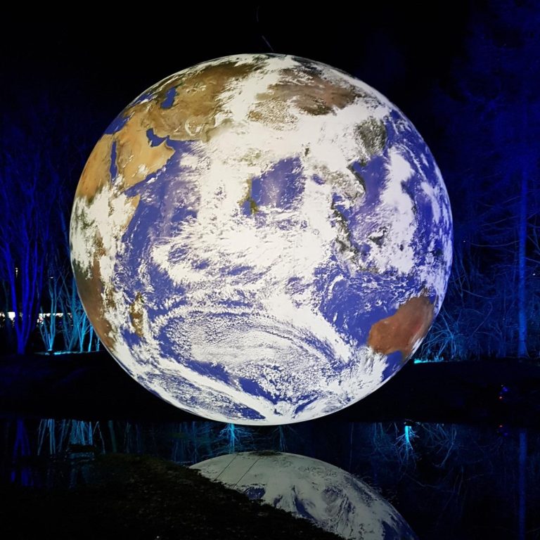 This image was taken at Helix Park, Falkirk at night. An image of the Earth partially reflected in a pool of water below it.